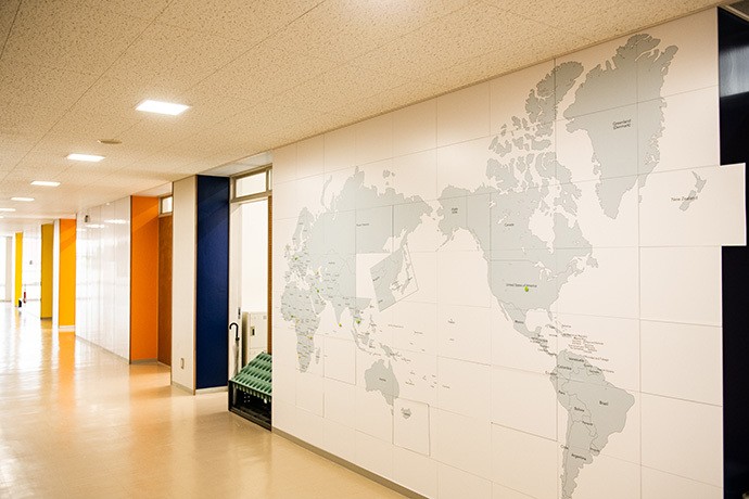 本科コースの廊下の壁一面の世界地図。日本が真ん中にある常識を疑ってほしいと、30センチ四方のピースは磁石で自由に動かせる